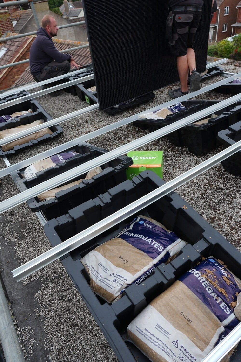 Fast Tub units loaded with ballast bags sitting directly on a gravel flat roof, secured by weight alone with no fixings through the membrane