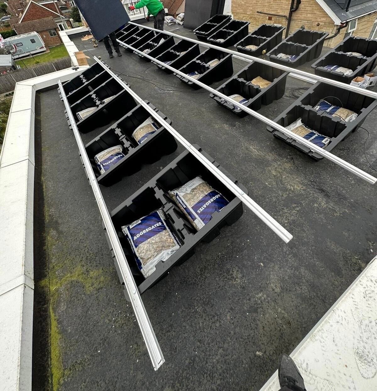 Installer stepping between ballasted Fast Tub units while aluminium rails are laid out across the roof